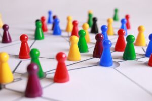 Decorative image representing linking leaders of colourful plastic games pieces standing on a sheet of paper with interconnecting lines.