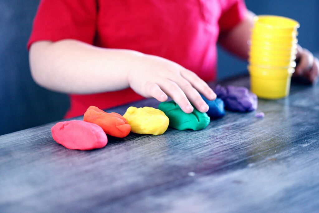 child lining up coloured balls of clay