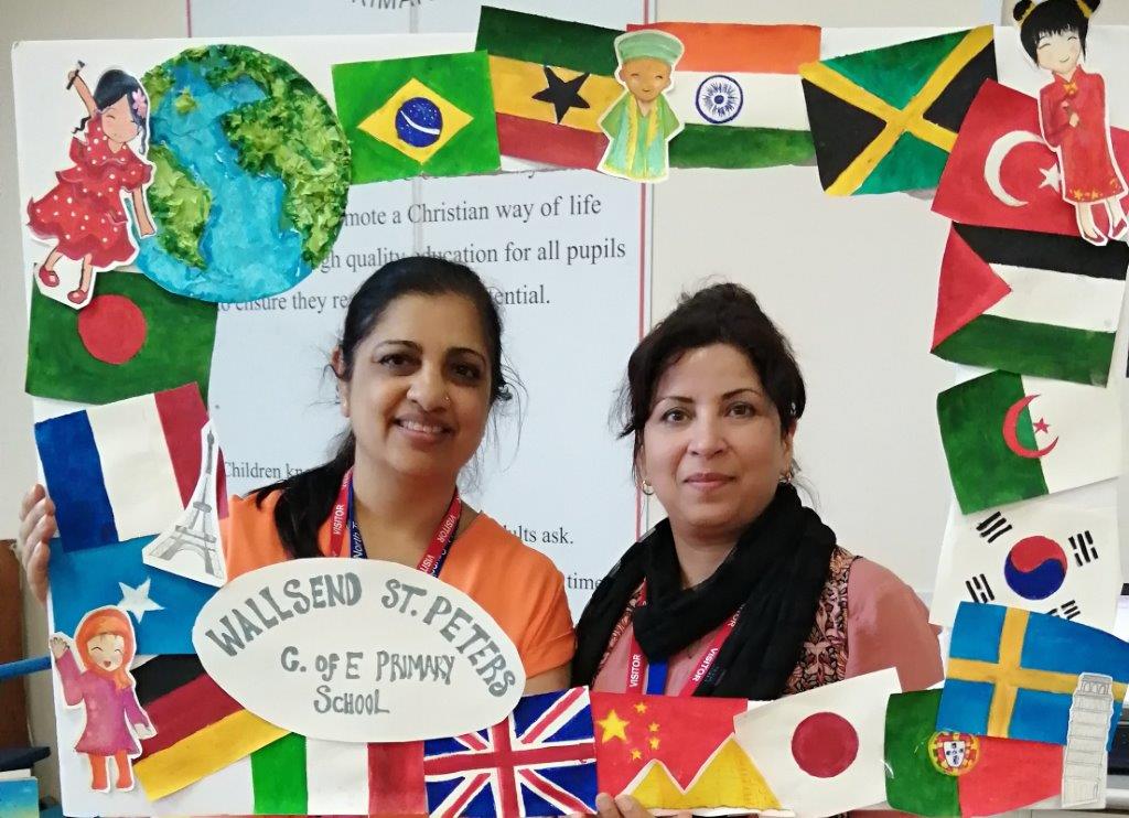 Members of the EMTAS Team photographed in the decorated selfie frame. The frame is covered in world flags.