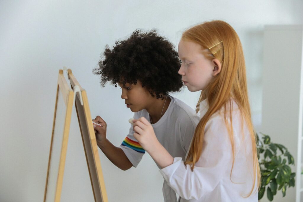 two children drawing on an easel side by side