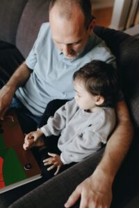 Father Holding A Book Beside His Child