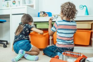 Two children playing with toys with their backs to the camera.